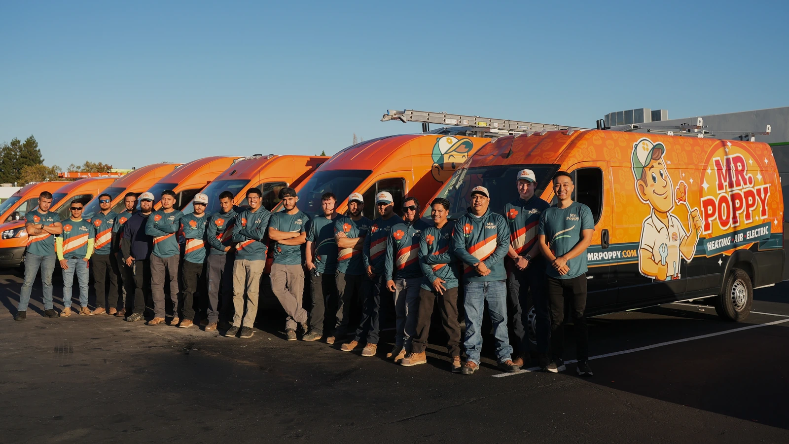 The Mr. Poppy team standing beside orange branded service vans.