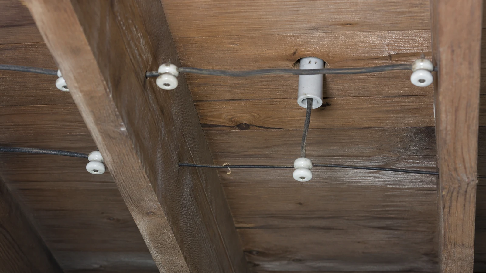 Representative service scene: older cloth-insulated wiring supported by porcelain knobs and tubes in an attic.